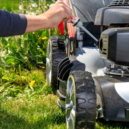 person checking the oil on a lawnmower