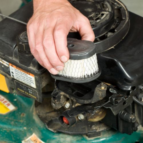 person removing the air filter from a lawnmower