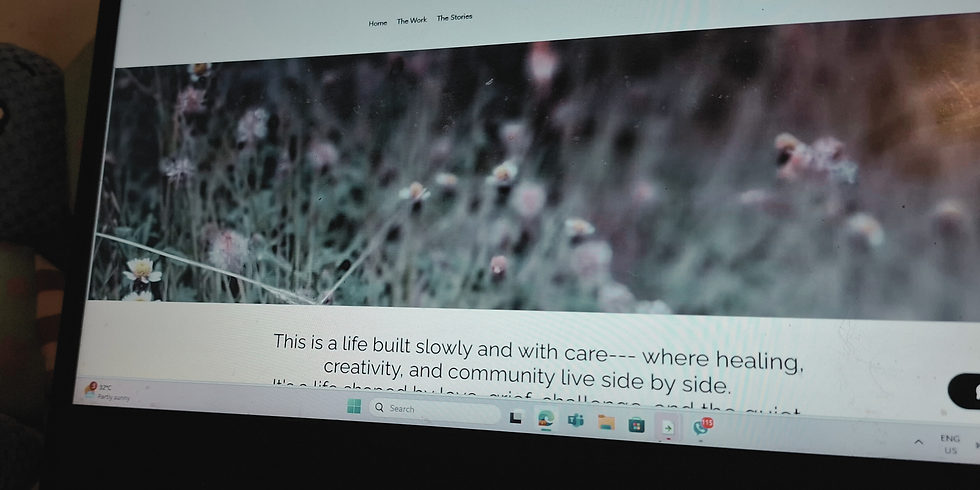 A softly blurred website banner showing a field of wildflowers in muted tones of green, pink, and purple. Above the image is a minimalist navigation menu with links: Home, The Work, The Stories. Below the banner, text reads: "This is a life built slowly and with care—where healing, creativity, and community live side by side."