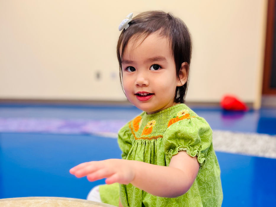 smiling toddler playing a drum at a Little Groove music class