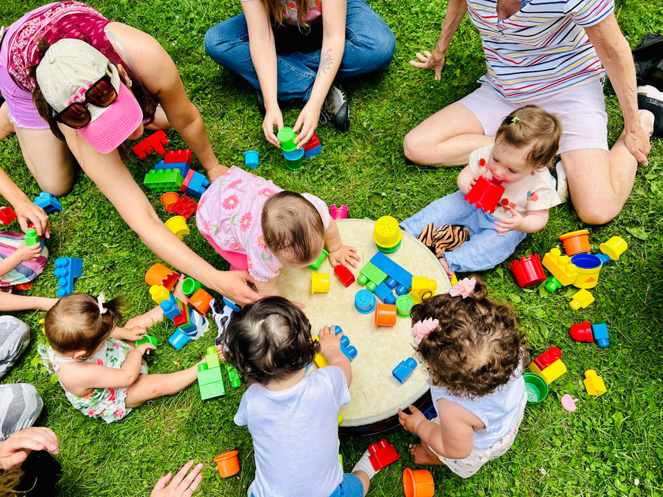 Babies playing with colorful blocks at an outdoor music class