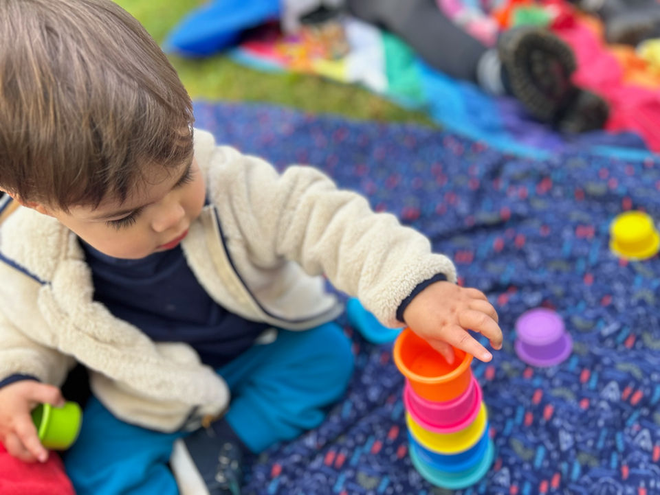 Toddler stacking colorful cups at a music class for kids