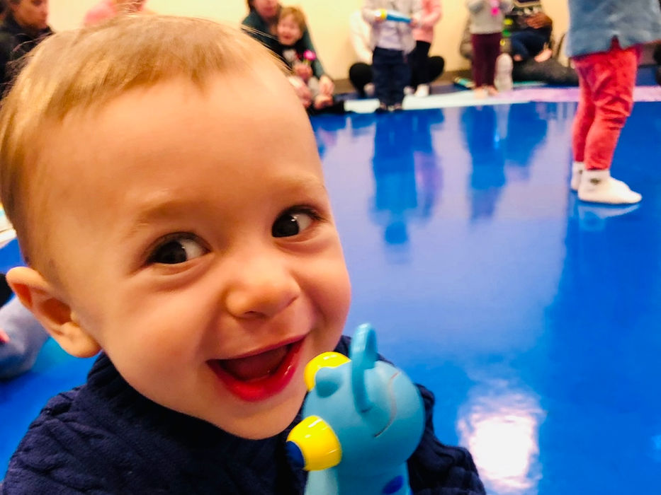 smiling toddler holding a toy at a Little Groove music class for kids in the Seaport Boston