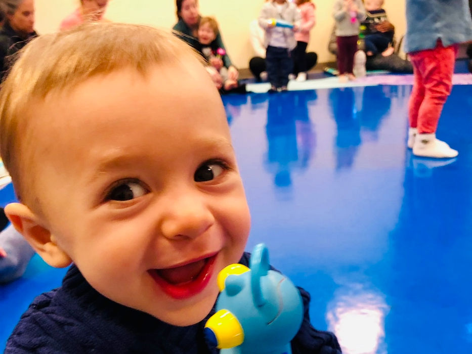 smiling toddler holding a toy at a Little Groove music class for children in Somerville
