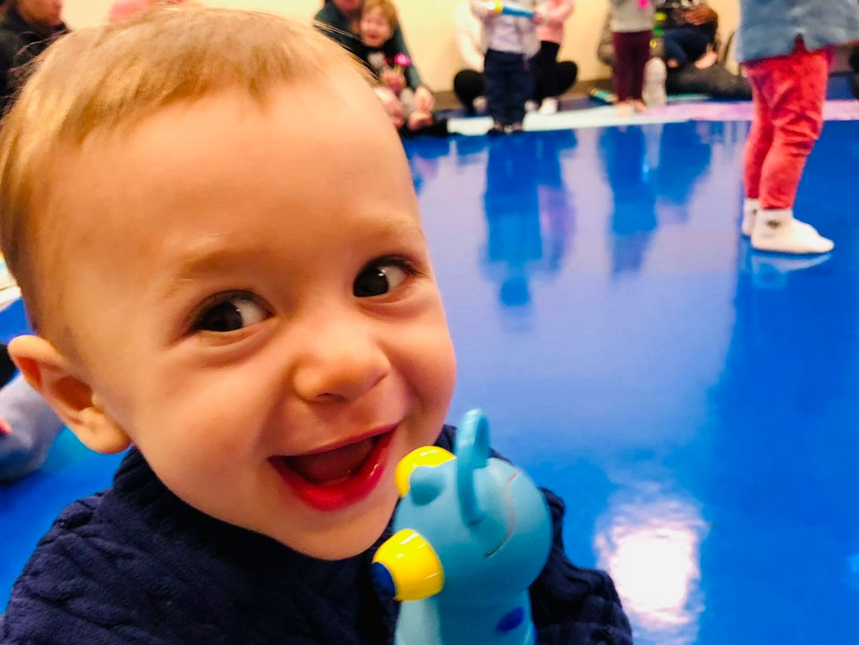 smiling toddler holding a toy at a Little Groove South Boston children's music class