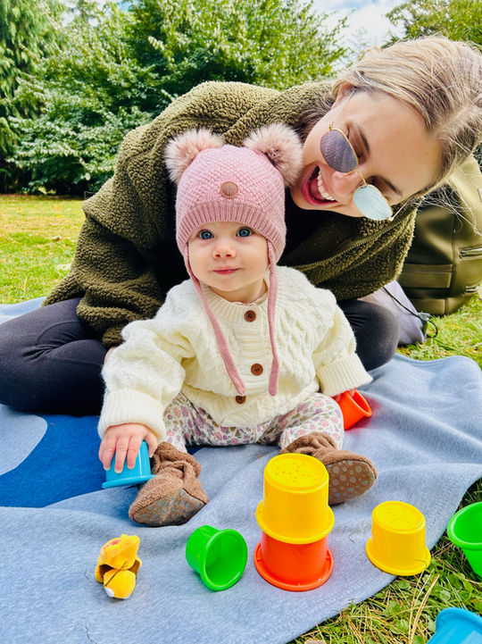 Baby and adult playing with colorful toys outdoors at a Little Groove music class