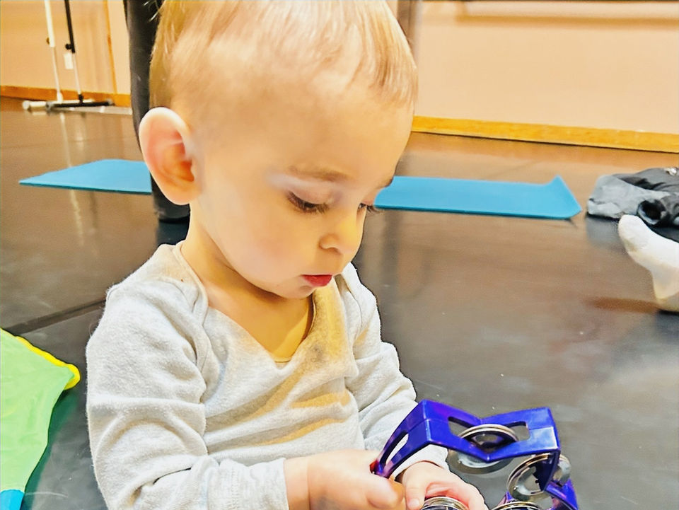 Young child playing with a blue musical toy on a dance studio floor