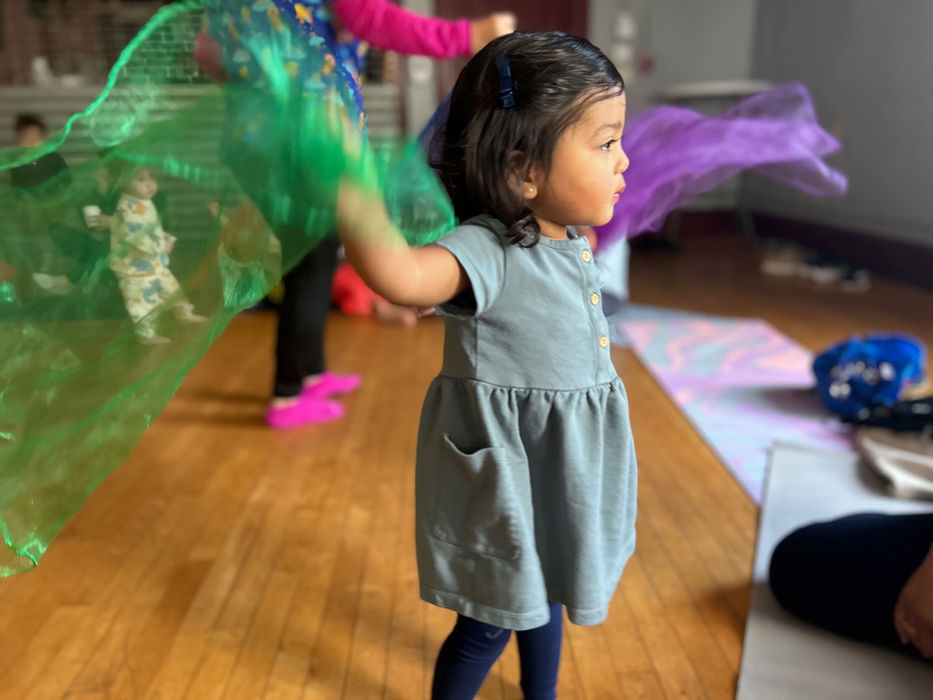 Young girl happily dancing with colorful scarves