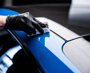 Car cash or car detailing studio worker applying graphene or ceramic coating on blue sport