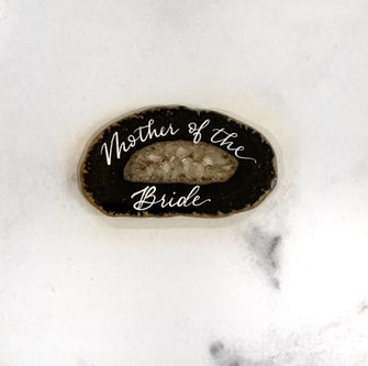 agate placecard with the name Mother of the Bride in white pointed pen calligraphy by sara wells nj luxury event calligrapher, engraver, hot foiling artist and bottle painter
