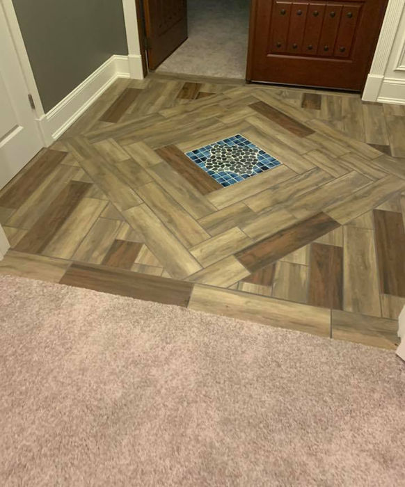 Remodeled hallway with patterned wood-look tile floor and decorative insert done by Precision Roofing And Remodeling
