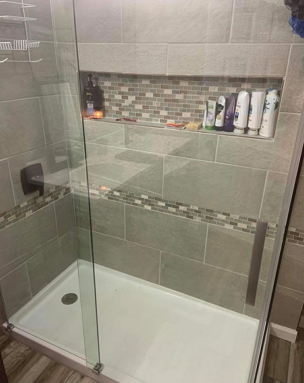 Modern custom tiled shower with glass door and niche