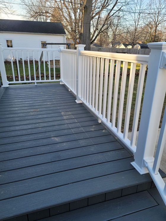 Remodeled deck with grey boards and white railings by Precision Roofing And Remodeling