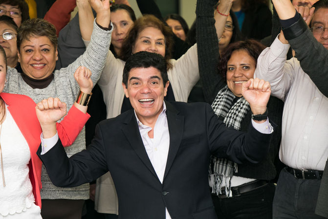a man in a suit is surrounded by people with their arms in the air