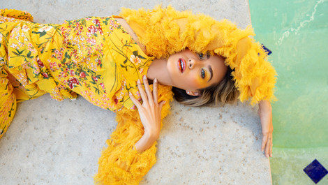 a woman in a yellow floral dress is laying on the ground