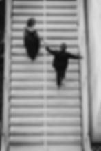 Couple holding hands while walking up outdoor stairs.