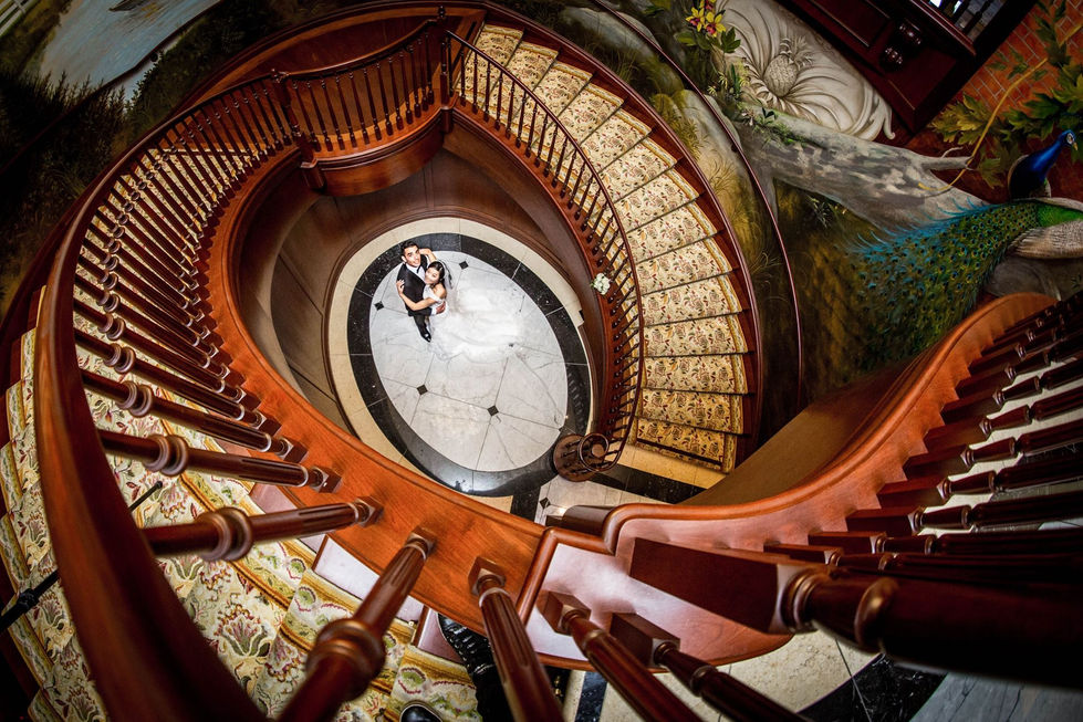 a bride and groom pose on a spiral staircase