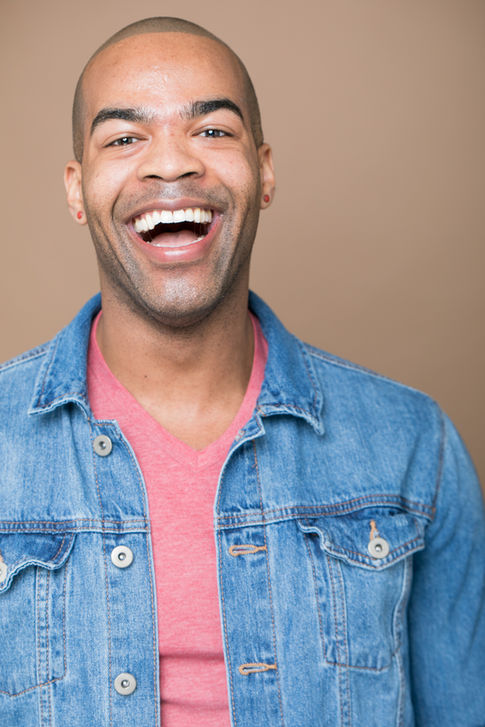 a man wearing a denim jacket and a pink shirt is laughing