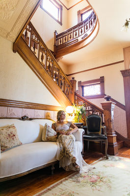 a woman sits on a couch in front of a staircase