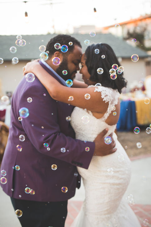 a bride and groom are dancing in front of soap bubbles