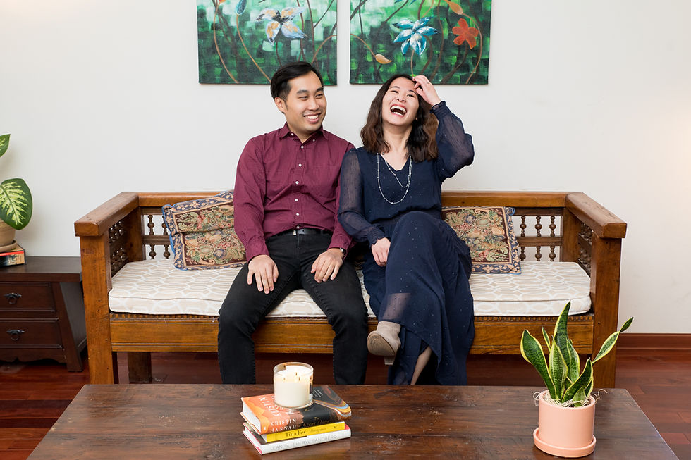 Couple laughing on a wooden couch during a photoshoot.