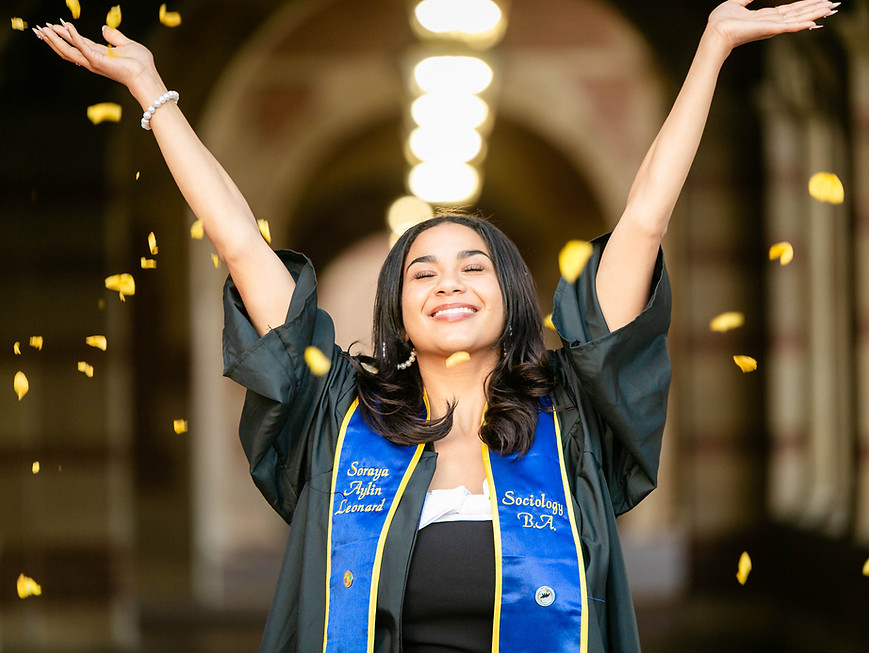 Graduate tossing yellow petals with orange county photographer