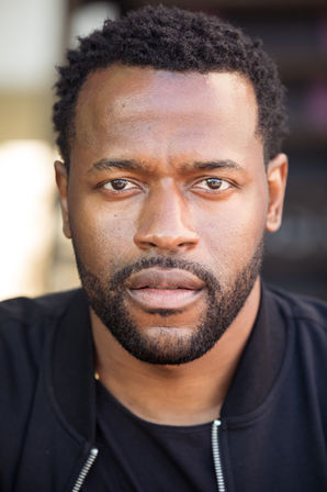 a man with a beard and a black shirt looks at the camera
