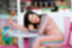 Woman in rainbow track suit laughing with a lollipop