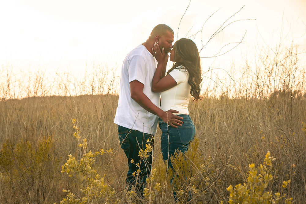 A couple embracing in a field by a couples photographer.