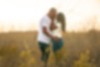 A couple embracing in a field by a couples photographer.