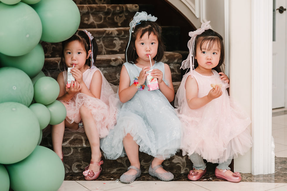 Three young girls sitting on stairs with juice boxes at a birthday party.