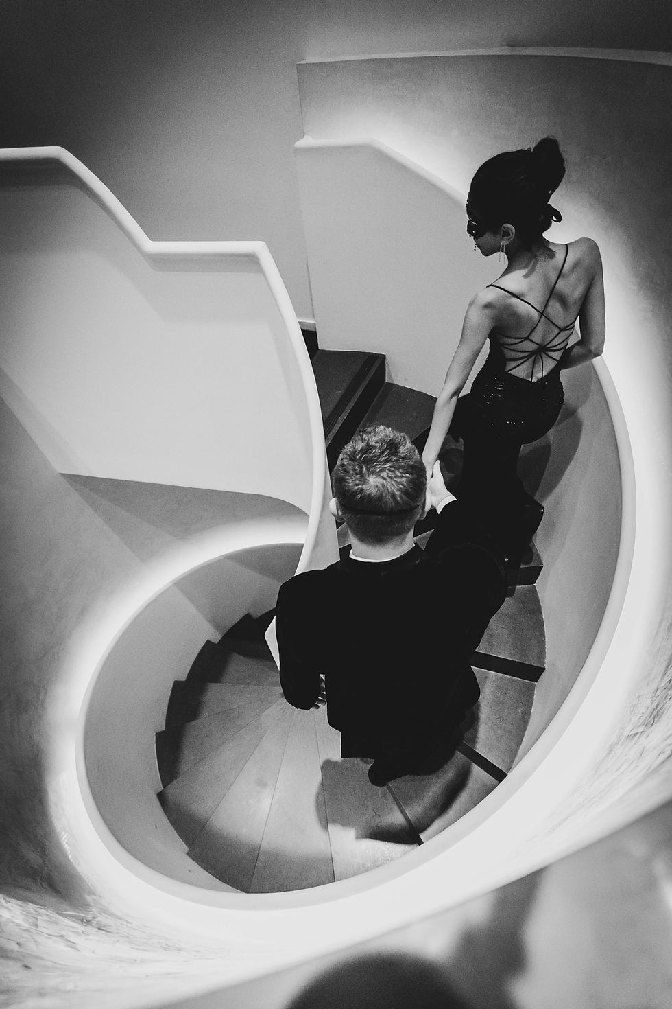 Black and white shot of a couple on a spiral staircase by a couples photographer.