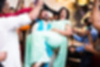 Woman in teal sari being lifted at a birthday party