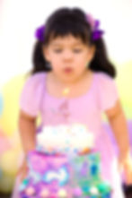 Young girl blowing out a number 4 candle on her birthday cake