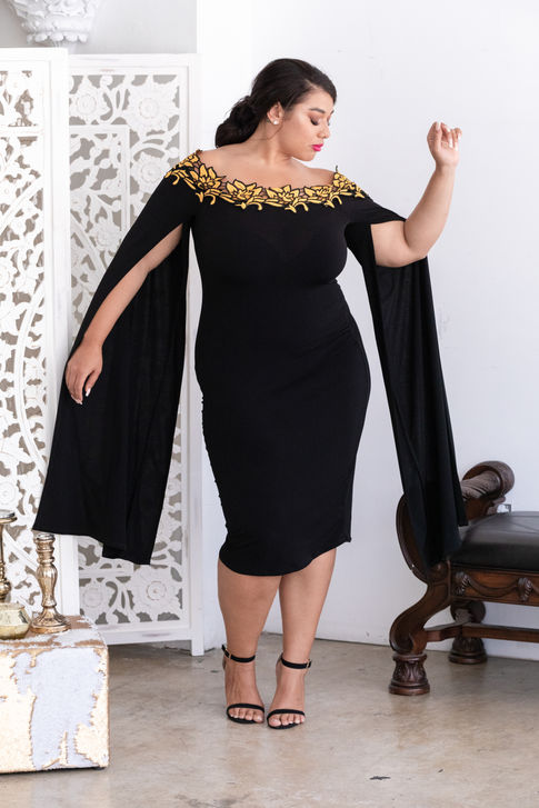 a woman in a black dress with gold embroidery on the shoulder