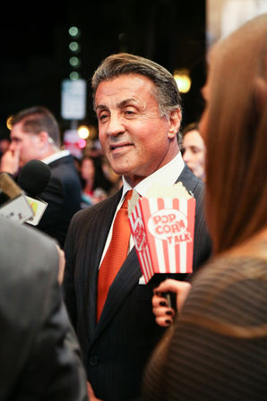 a man in a suit is holding a popcorn bucket that says pop corn talk