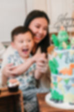 Mother and son cutting dinosaur cake at birthday party.