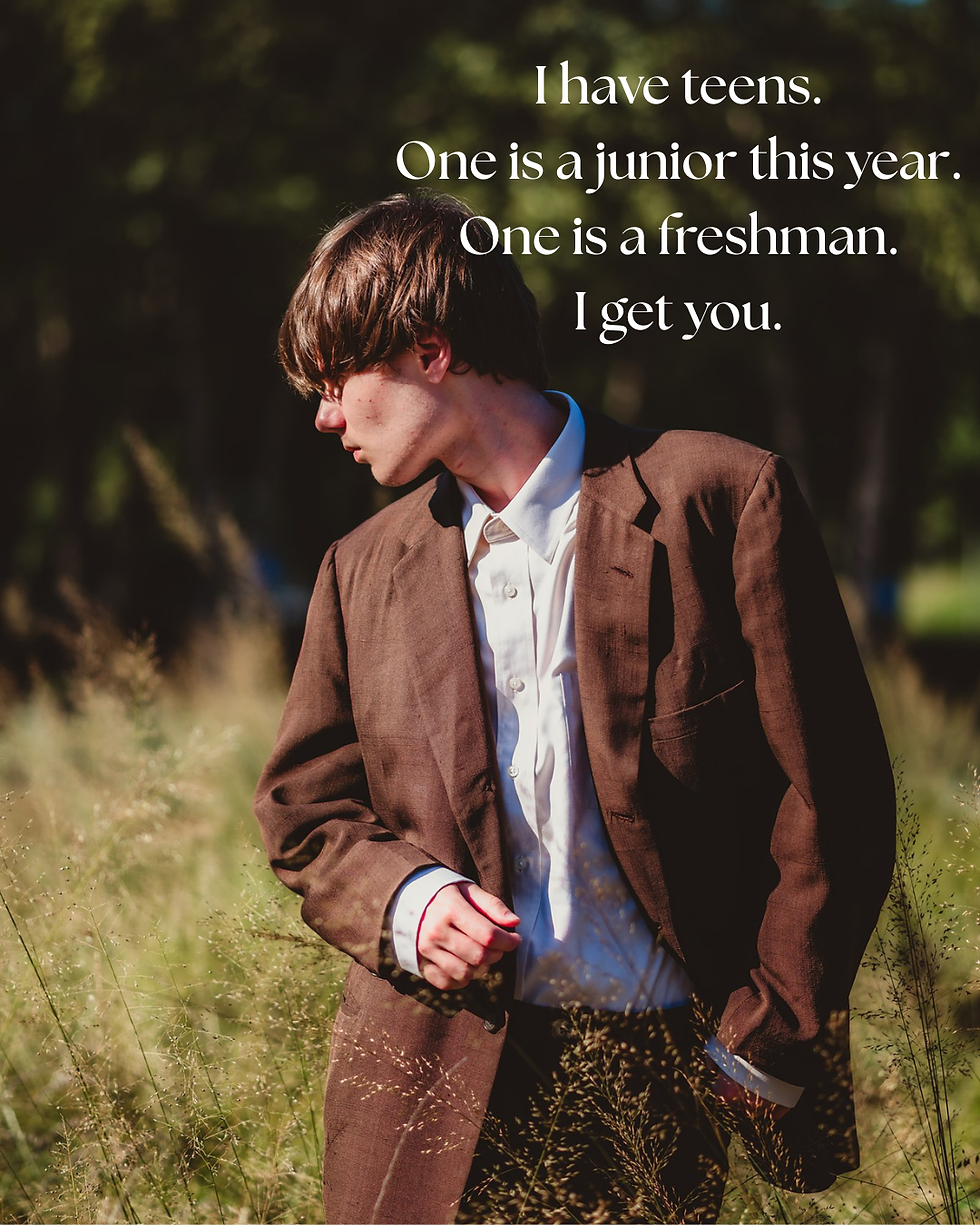 A teenage boy looks away from the camera while wearing a brown suit in a field of tall grass for his senior pictures in Raleigh, North Carolina.