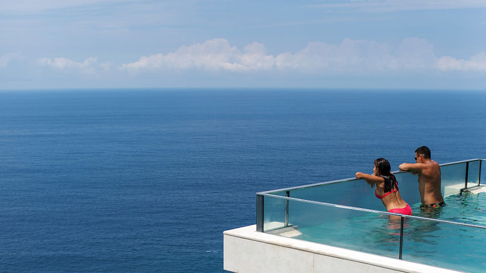 Couple relaxing in an infinity pool overlooking the open ocean with clear blue skies and panoramic sea views.