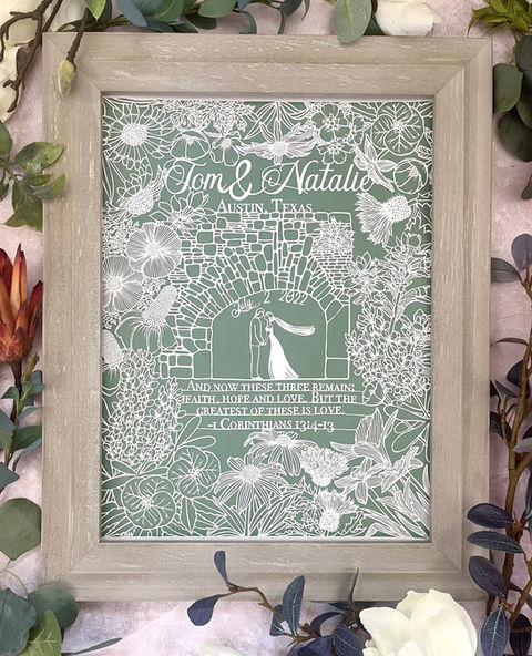 A papercut artwork depicting a bridal couple under a stone arch and surrounded by Texas wildflowers.