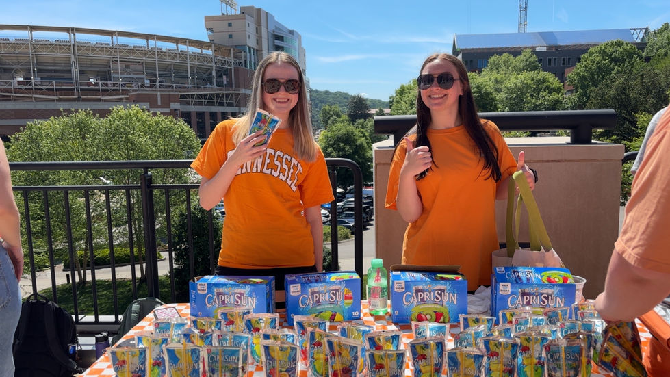 Haley Lawson and classmate standing in front of table on pedestrian walkway bridge on UTK campus for a marketing project