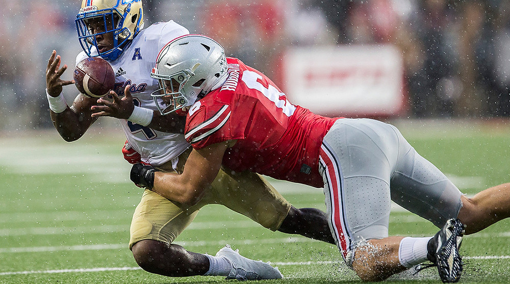Football player tacking wide receiver who is catching a pass