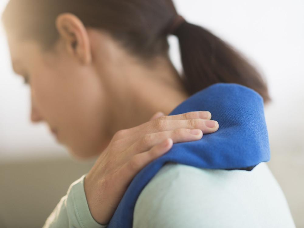 Women placing cold compress onto sore shoulder