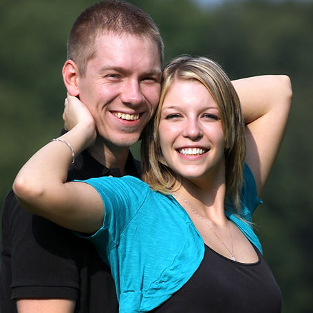 Jess and future hubby smile at the camera. He is holding her from behind.