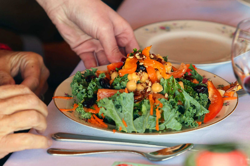 A colorful wedding salad being placed in front of a guest.