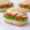 Mini sándwiches de pavo con naranja, tomate y lechuga, listos para cócteles o eventos.