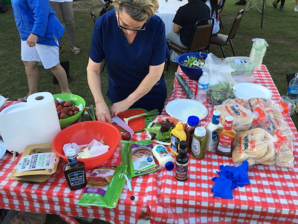 Woman preparing food at an outdoor community event.