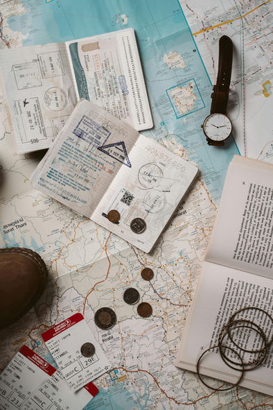 Prebuilt Itineraries; Passports and travel tickets on a paper map with coins, a book and a wristwatch