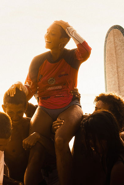 Surfer being lifted up and sitting on the shoulders of a local beach community at sunset