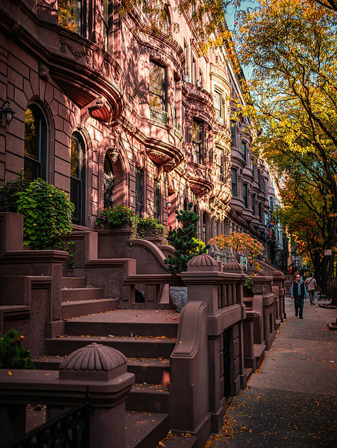 kior-travel-about-us-Sunlit-brownstone-row-houses-on-a-tree-lined-New-York-City-Street-in-autumn